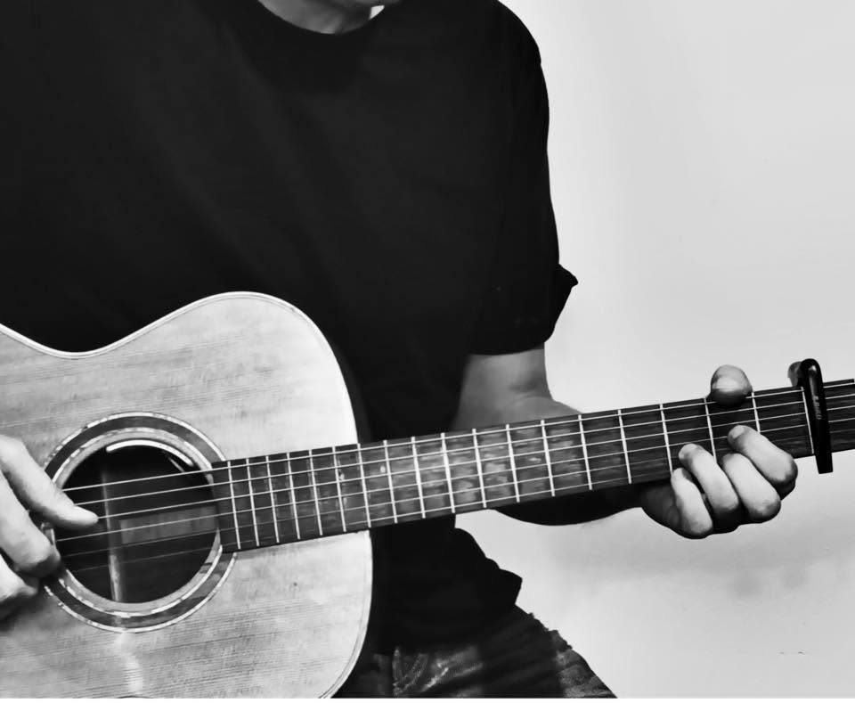 Hands playing an acoustic guitar during a one-to-one music lesson