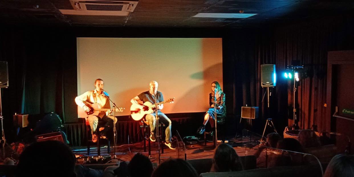 Ryan Edwards in an acoustic trio on a dark stage with warm and cool light